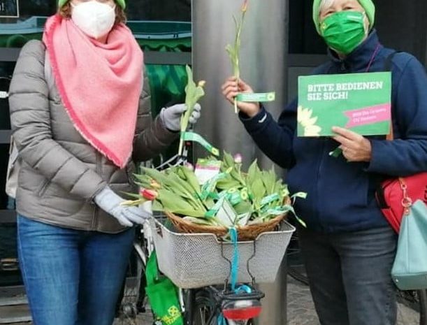 Zwei Grüne verteilen Blumen
